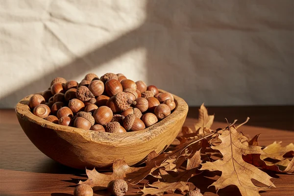 Fresh acorns scattered on a warm walnut surface beside rustic winemaking equipment in soft natural light