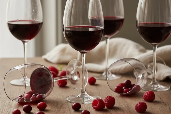 Cranberry and raspberry wine in a rustic glass on a walnut surface with soft natural light
