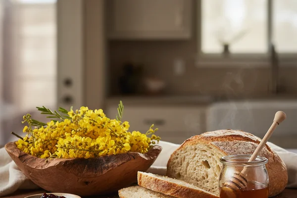 Huisache tree blossoms in warm golden light on a walnut surface with cream linen backdrop