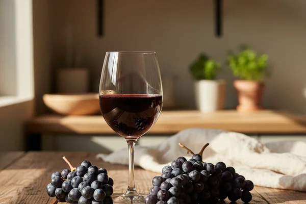 Cluster of muscadine grapes beside a one-gallon glass wine jug on a warm walnut surface in soft natural light